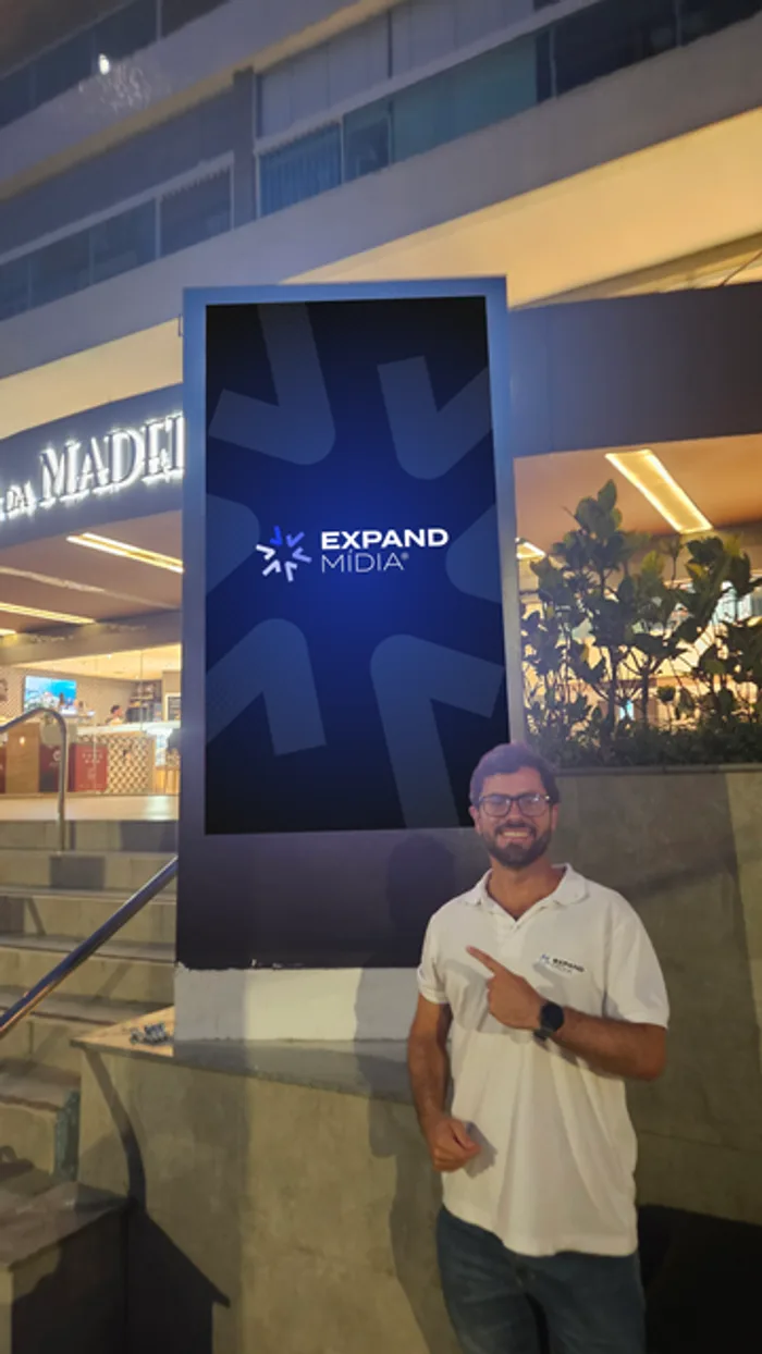 Franqueado Expand Mídia apresentando totem digital instalado em ponto comercial