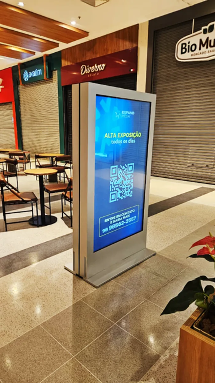 Totem digital Expand Mídia em shopping, exibindo anúncio de espaço publicitário disponível